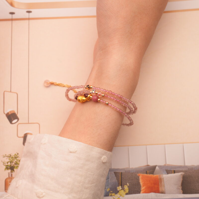 The bracelet wrapped around the wrist three times, showcasing the feminine blend of rose quartz and rhodochrosite in a stacked style.