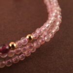 Close-up of rose quartz and rhodochrosite beads, revealing smooth surfaces and delicate natural textures.
