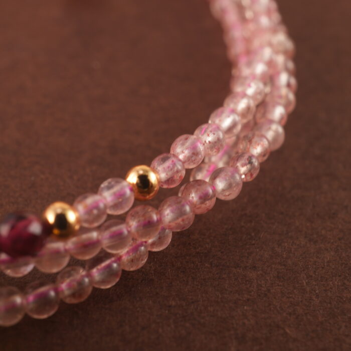Close-up of rose quartz and rhodochrosite beads, revealing smooth surfaces and delicate natural textures.