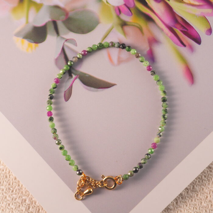 Ruby zoisite bracelet displayed in natural light on rustic surface.