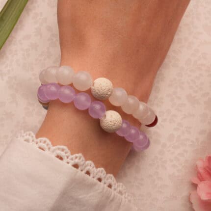 Model wearing gemstone bracelet stack with lava textures.