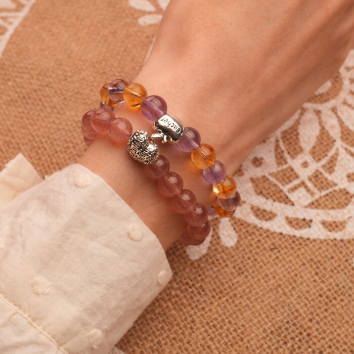 Model wearing layered ametrine and strawberry quartz bracelets.
