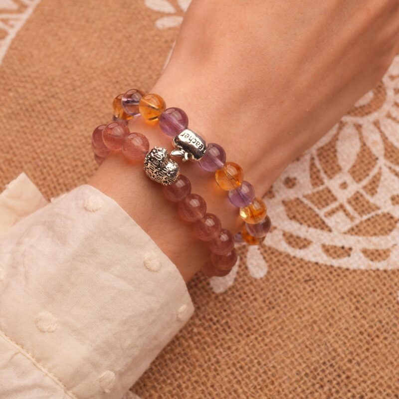 Model wearing layered ametrine and strawberry quartz bracelets.