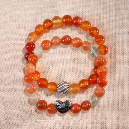 Flatlay of stacked bracelets featuring Arusha sunstone and flower red agate.
