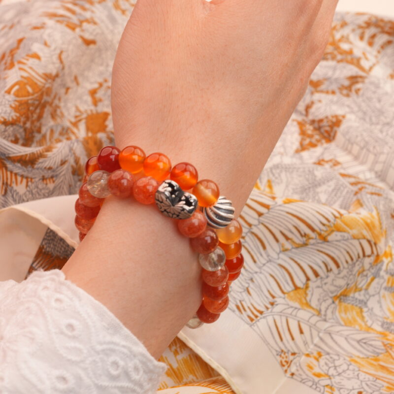 Model wearing Arusha sunstone and flower red agate bracelets on wrist.