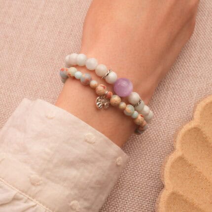 Model wearing stacked gemstone and silver bracelets.