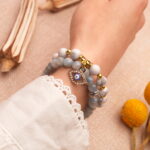 Model wearing gemstone stack in vibrant blue, red, and white tones.