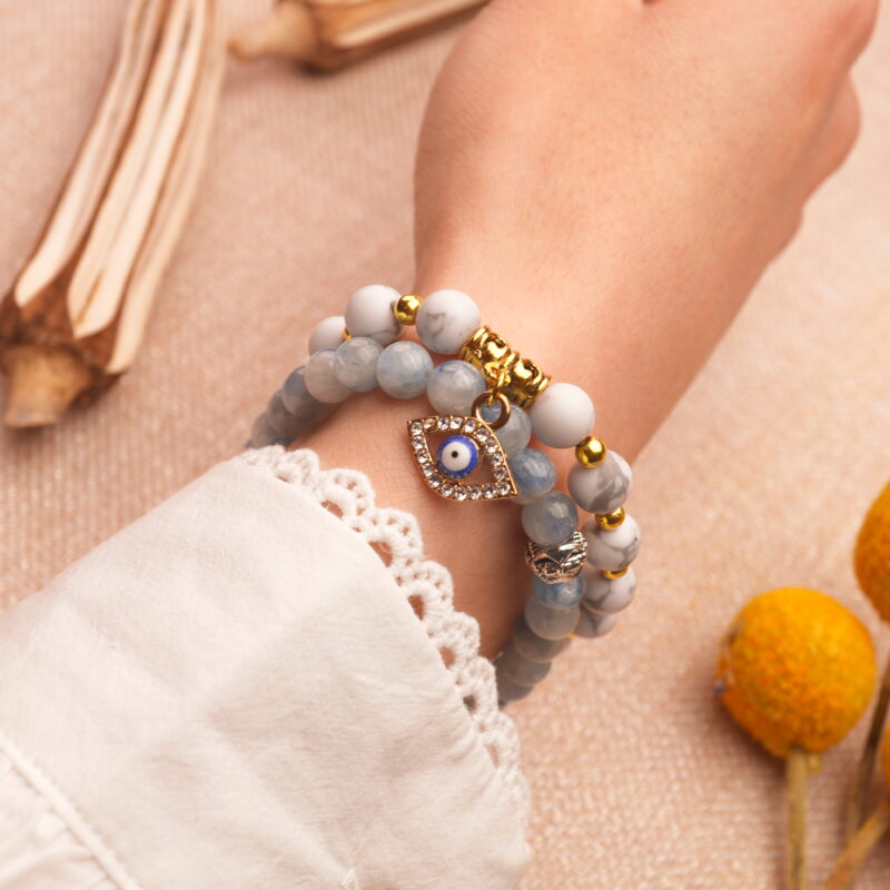 Model wearing gemstone stack in vibrant blue, red, and white tones.