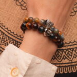 Model wearing gemstone stack in bold blue and brown tones.