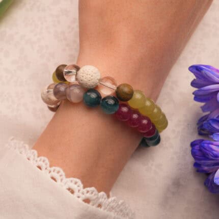 Model wearing stacked bracelets in light and dark tones.