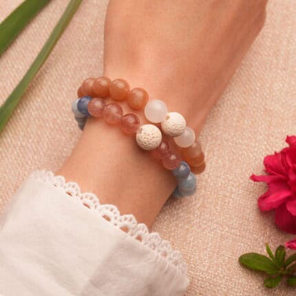 Model wearing layered bracelets with gemstone and lava textures.