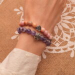 Model wearing pink and purple gemstone stacked bracelets.