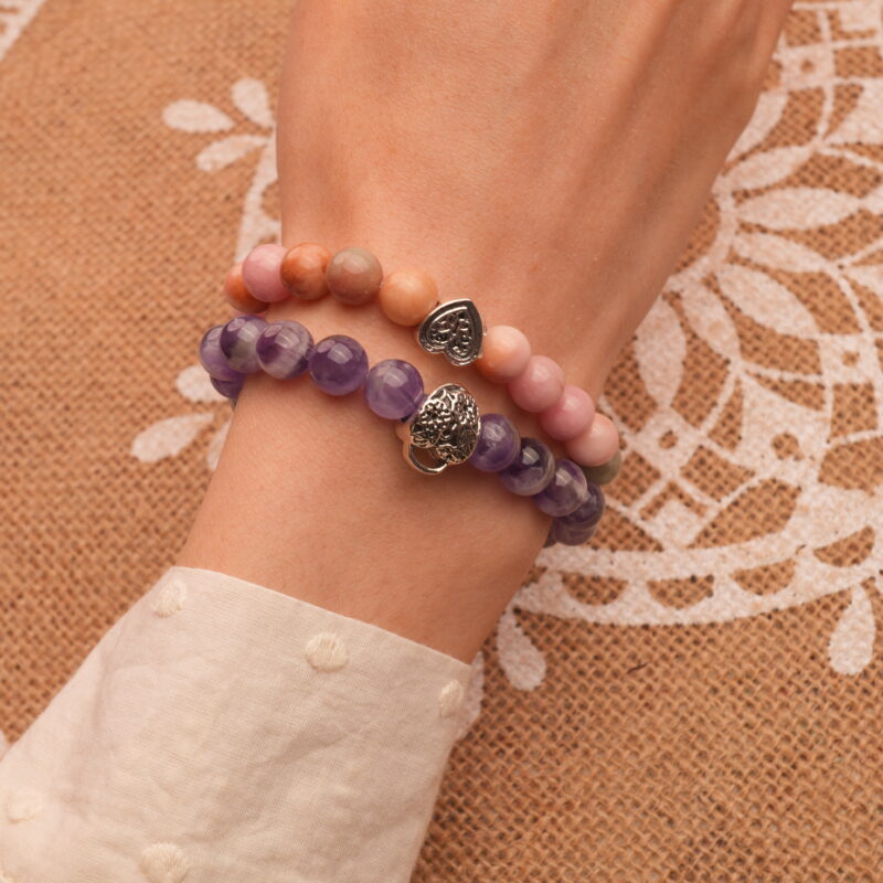 Model wearing pink and purple gemstone stacked bracelets.