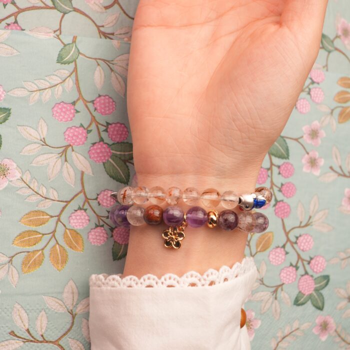 Model wearing soft purple and golden-toned gemstone stack.