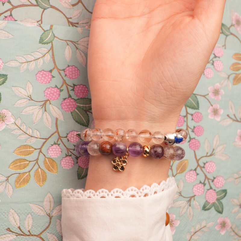 Model wearing soft purple and golden-toned gemstone stack.
