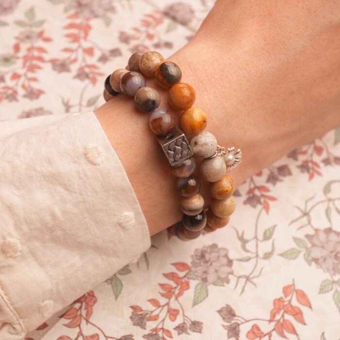 Model wearing stacked earthy and cool-toned gemstone bracelets.
