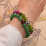 Model wearing stacked tourmaline and aventurine-red agate bracelets on wrist.