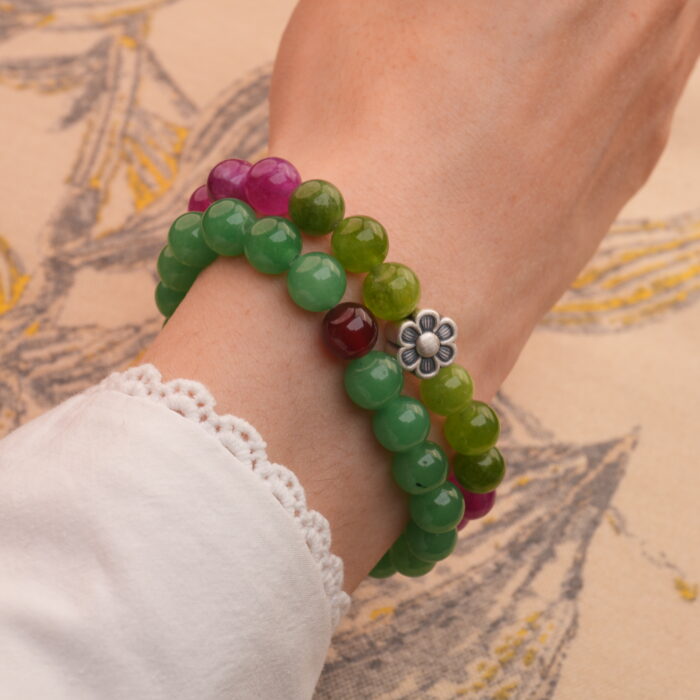 Model wearing stacked tourmaline and aventurine-red agate bracelets on wrist.