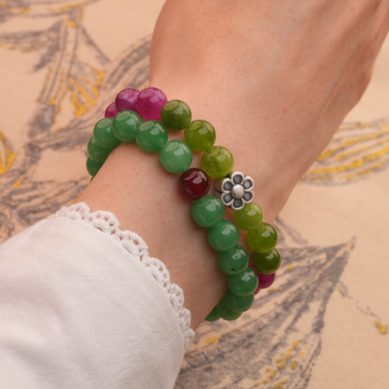 Model wearing stacked tourmaline and aventurine-red agate bracelets on wrist.