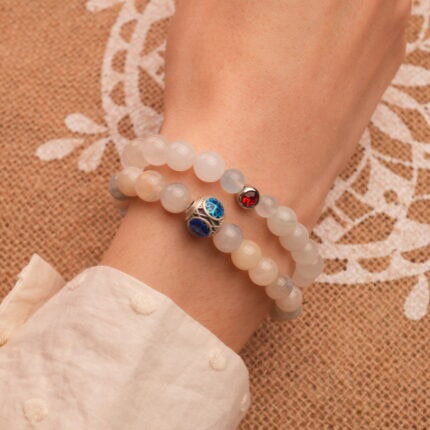 Model wearing gemstone bracelet stack with cool and bold tones.