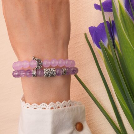 Model wearing two stacked amethyst bracelets on wrist.