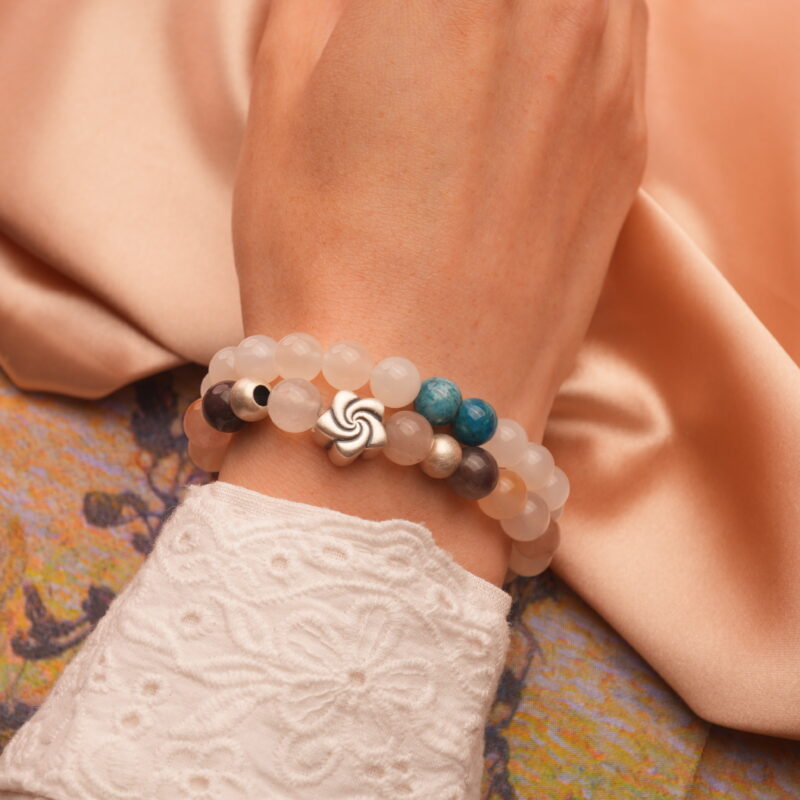 Model wearing moonstone, apatite, and aventurine stacked bracelets on wrist.