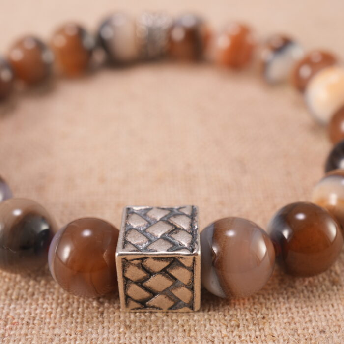 Close-up of striped agate bracelet with S925 silver charm.