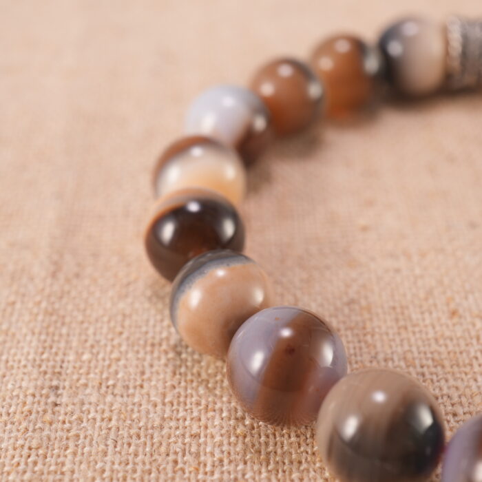 Close-up of striped agate bracelet with S925 silver charm.