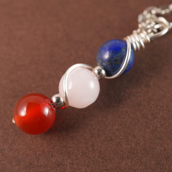 Close-up of Taurus necklace showing lapis lazuli, clear quartz, and red agate beads.