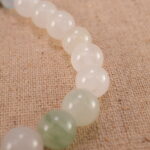 Close-up of white chalcedony and ruby bracelet with S925 silver charm.