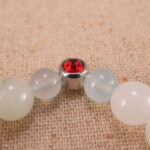 Close-up of white chalcedony and ruby bracelet with S925 silver charm.