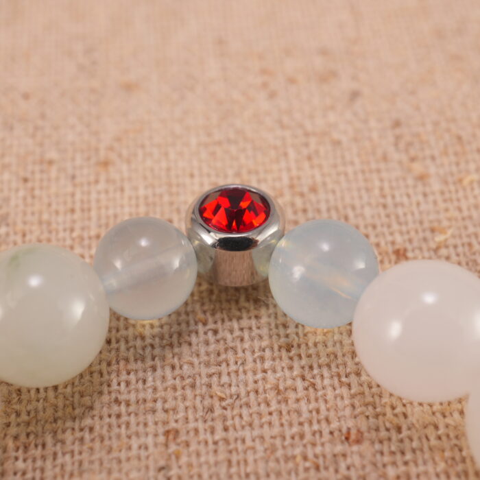 Close-up of white chalcedony and ruby bracelet with S925 silver charm.
