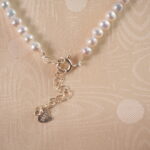 Detailed view of the adjustable pearl necklace's clasp and chain mechanism, showing pearl texture and adjustable features.