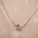 Detailed view of the adjustable pearl necklace's clasp and chain mechanism, showing pearl texture and adjustable features.