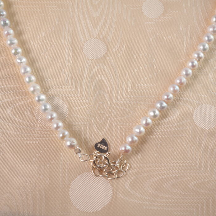Detailed view of the adjustable pearl necklace's clasp and chain mechanism, showing pearl texture and adjustable features.