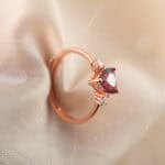 Close-up view of the heart-cut garnet and rose gold band, showing the fine polish and setting.