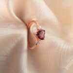 Close-up view of the heart-cut garnet and rose gold band, showing the fine polish and setting.