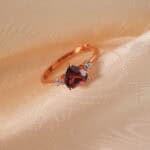 Close-up view of the heart-cut garnet and rose gold band, showing the fine polish and setting.