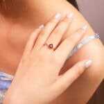 Heart-shaped garnet ring worn on the finger, highlighting its elegant charm and warm red tone.