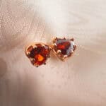 A pair of garnet heart stud earrings featuring a rich red hue and elegant craftsmanship.