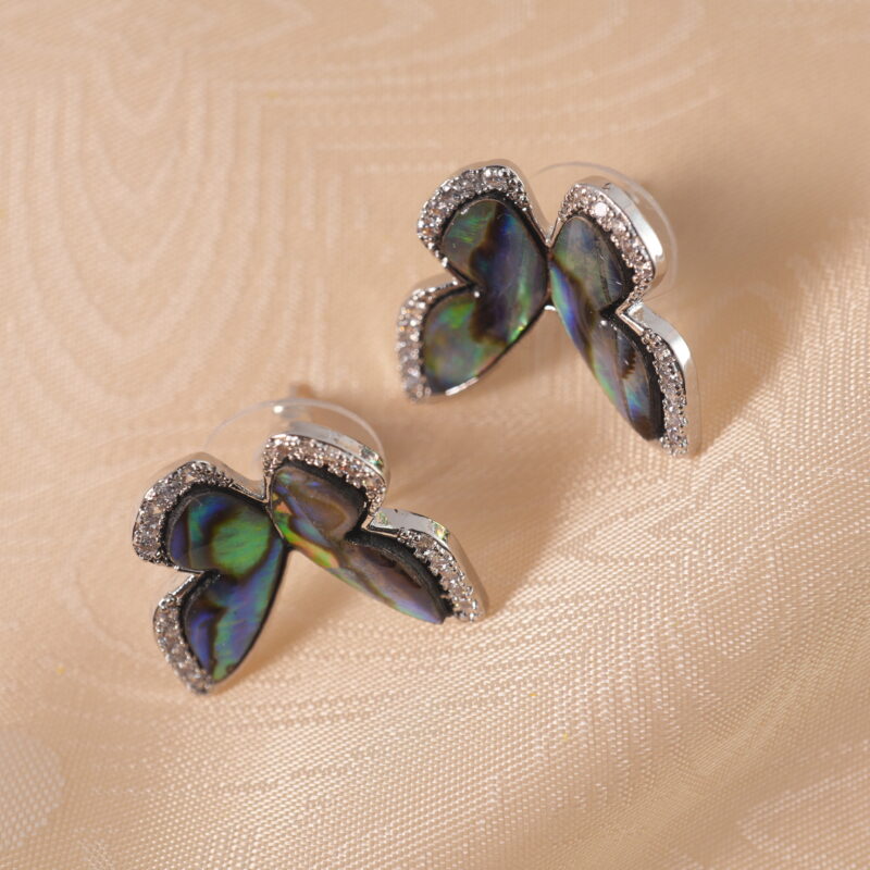 A pair of butterfly-shaped moonstone stud earrings on a white background, displaying a soft iridescent glow.
