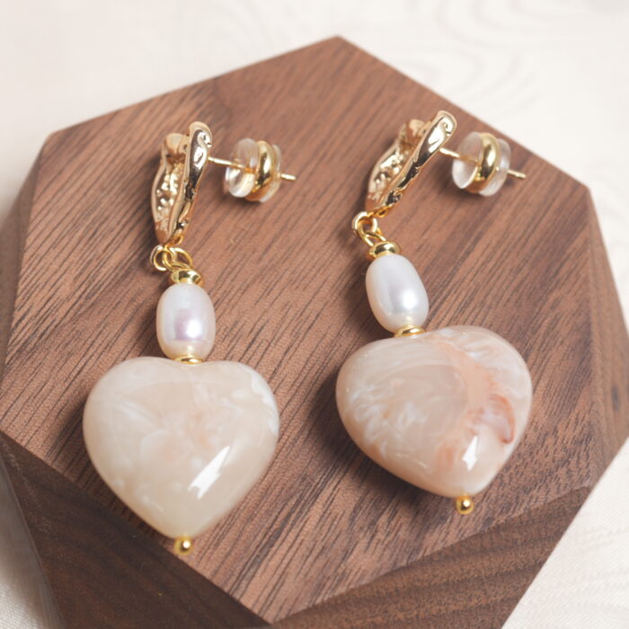 Close-up of the pearl earring, highlighting the lustrous pearl and fine metallic detailing.