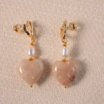 A pair of heart-shaped pearl drop earrings displayed on a white background, showcasing elegant and romantic design.