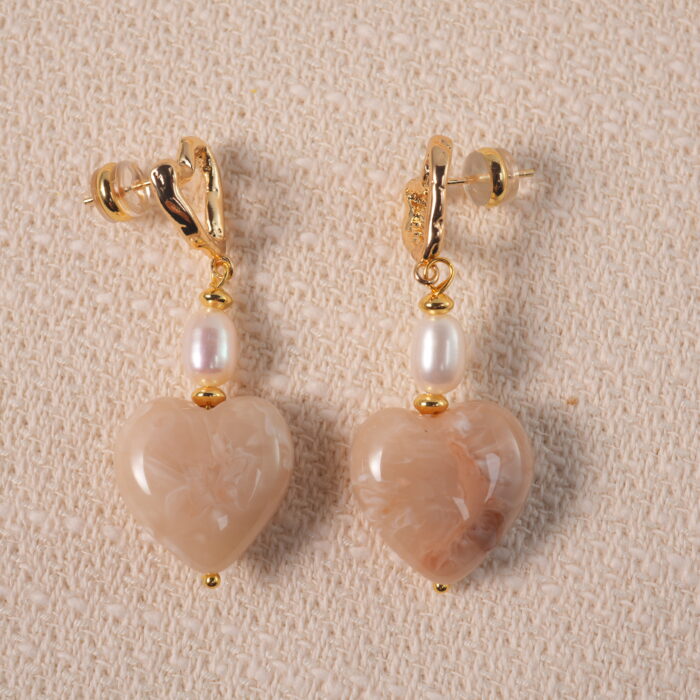 A pair of heart-shaped pearl drop earrings displayed on a white background, showcasing elegant and romantic design.