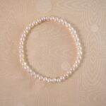A lustrous pearl stretch bracelet laid flat on a white background, highlighting its classic and elegant design.