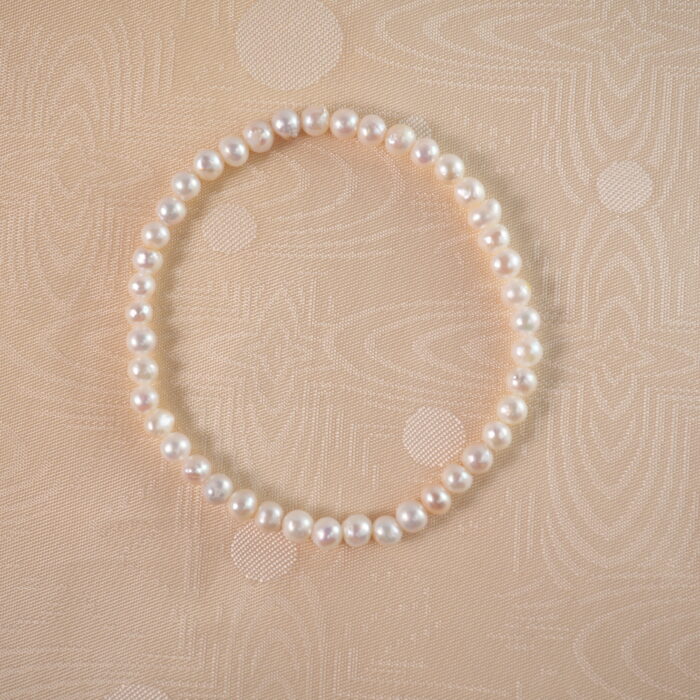 A lustrous pearl stretch bracelet laid flat on a white background, highlighting its classic and elegant design.