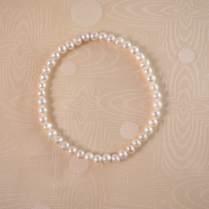 A lustrous pearl stretch bracelet laid flat on a white background, highlighting its classic and elegant design.