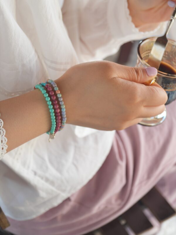 A girl is drinking coffee with 3 bracelets.