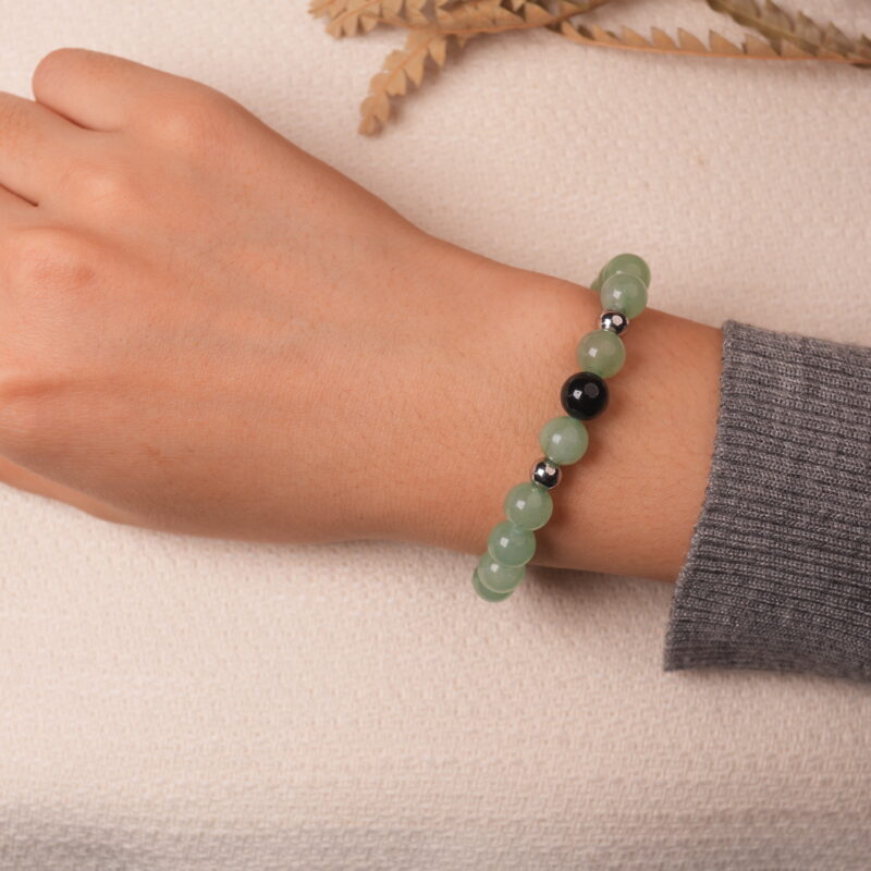 A hand wearing the Green Aventurine and Obsidian bracelet, showing the combination of green aventurine and black obsidian beads with a touch of silver spacers.