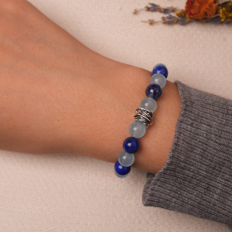 A hand wearing the Aquamarine and Lapis Lazuli bracelet, showcasing the soothing blue and vibrant lapis beads with the modern silver spacer in the center.